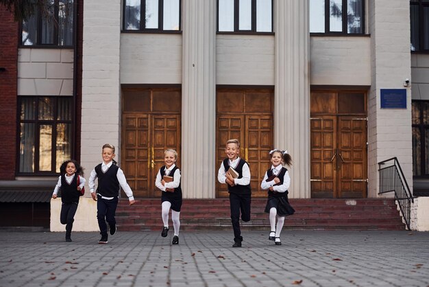 Gruppo di bambini in uniforme scolastico che corrono insieme all'aperto