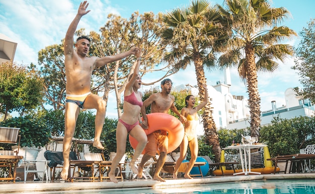 Gruppo di bei giovani divertendosi saltando insieme nella piscina.