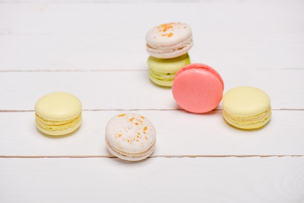 Gruppo di bei macarons variopinti sulla tavola di legno bianca Dolci sfondo