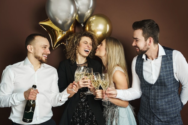 Gruppo di belle persone ben vestite che celebrano vacanze o eventi e bevono spumante