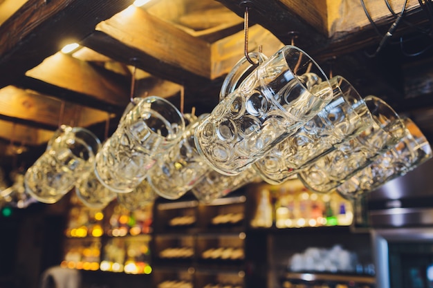 Gruppo di bicchieri di vino vuoti che pendono dalle travi di metallo in una barra.