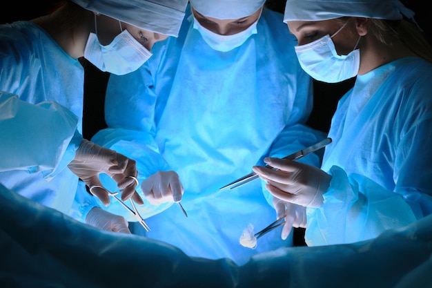 Gruppo di chirurghi al lavoro in sala operatoria tonica in blu. Equipe medica che esegue l'operazione
