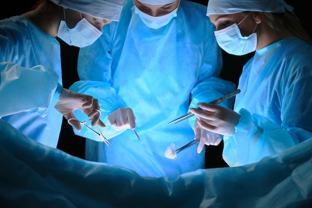 Gruppo di chirurghi al lavoro in sala operatoria tonica in blu. Equipe medica che esegue l'operazione