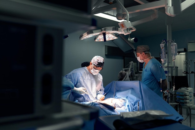 Gruppo di chirurghi che eseguono interventi chirurgici in sala operatoria ospedaliera Equipe medica che esegue operazioni critiche