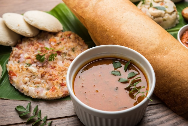 Gruppo di cibo dell'India meridionale come Masala Dosa, Uttapam, Idli o pigramente, Wada o vada, sambar, appam, semolina halwa, upma servito su foglie di banana con chutney colorati, messa a fuoco selettiva