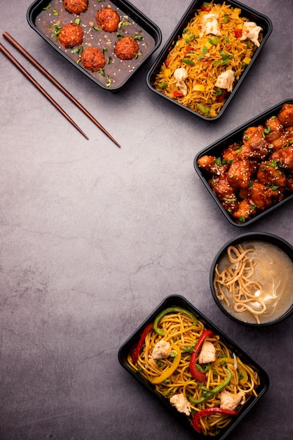 Gruppo di cibo indo cinese consegnato a casa in confezioni di plastica, contenitori o scatole contenenti spaghetti schezwan, riso fritto, pollo al peperoncino, manciuria e zuppa.
