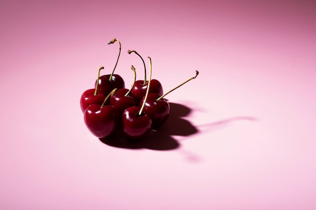 Gruppo di ciliegie su sfondo rosa con spazio di copia