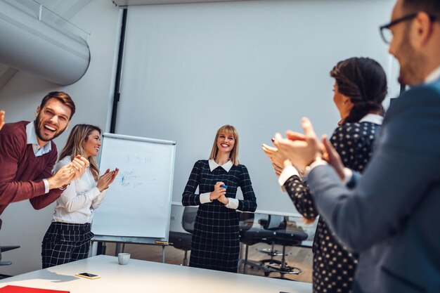 Gruppo di colleghi che applaudono durante il loro incontro in un ufficio moderno