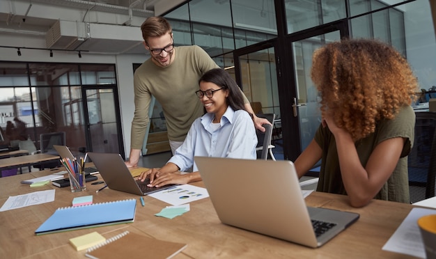 Gruppo di colleghi felici team di lavoro multirazziale che lavora seduti nel moderno spazio di coworking