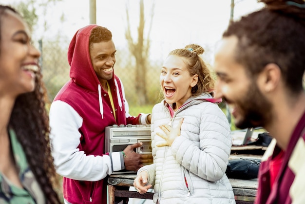 Gruppo di coppie di amici multirazziali che si divertono al parco in autunno inverno - concetto di amicizia giovanile con persone insieme all'aperto - Focus sulla giovane donna bionda