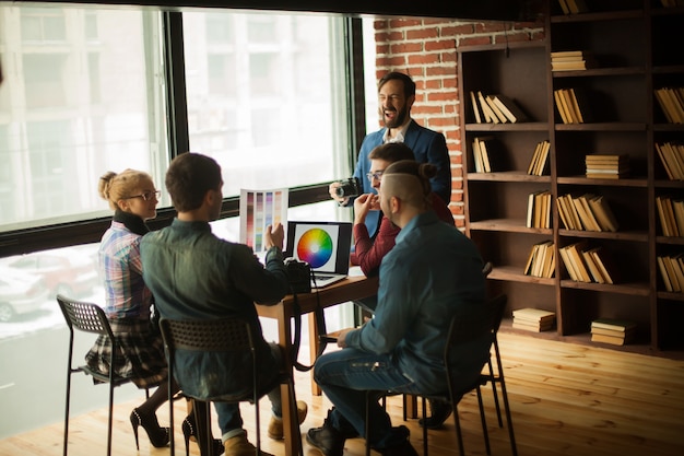 Gruppo di designer creativi che discutono di una nuova tavolozza di colori sul posto di lavoro in un ufficio moderno