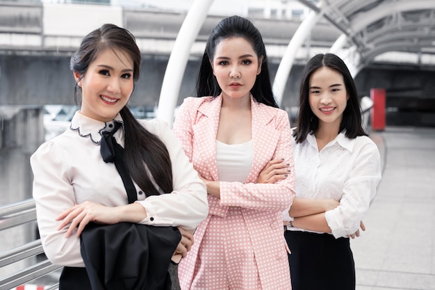 Gruppo di donna d'affari asiatica incrocia il braccio con un sorriso all'aperto in città. Concetto di lavoro di squadra donna asiatica. Gruppo tailandese dell'impiegato di concetto delle donne.