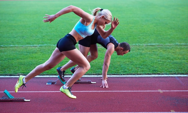 gruppo di donne atleta che corre sulla pista di atletica leggera sullo stadio di calcio e rappresenta il concetto di concorrenza e leadership nello sport