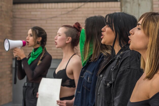 Gruppo di donne che marciano in segno di protesta Giovane donna che tiene cartello con slogan femministi