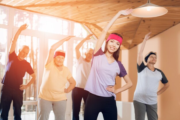 Gruppo di donne e uomini anziani che fanno ginnastica terapeutica.