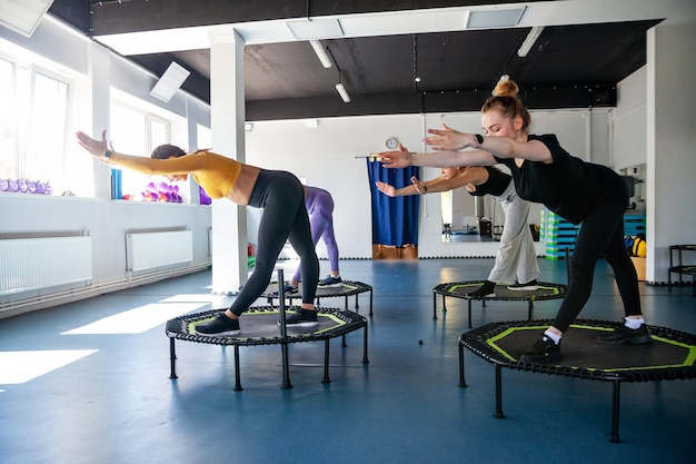 Gruppo di donne felici che si riscaldano prima dell'allenamento in palestra saltando sul trampolino