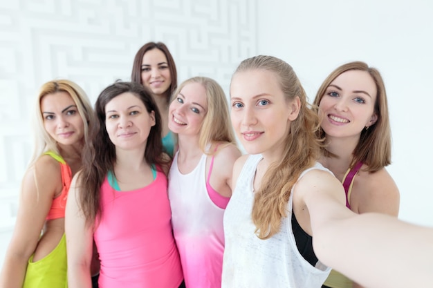 Gruppo di donne sportive felici che sorridono e si fanno un selfie