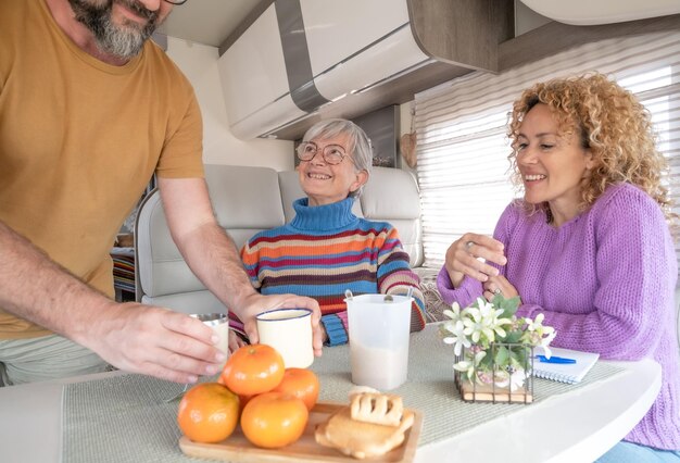 Gruppo di famiglia o amici felici stanno insieme all'interno di un camper durante la pausa caffè