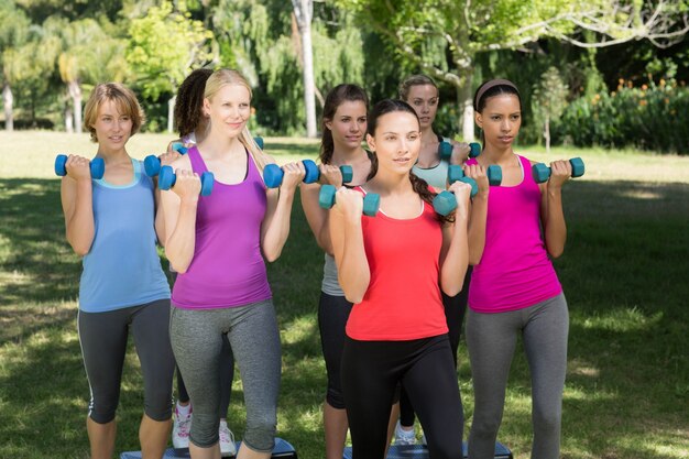 Gruppo di forma fisica che solleva i pesi a mano nel parco