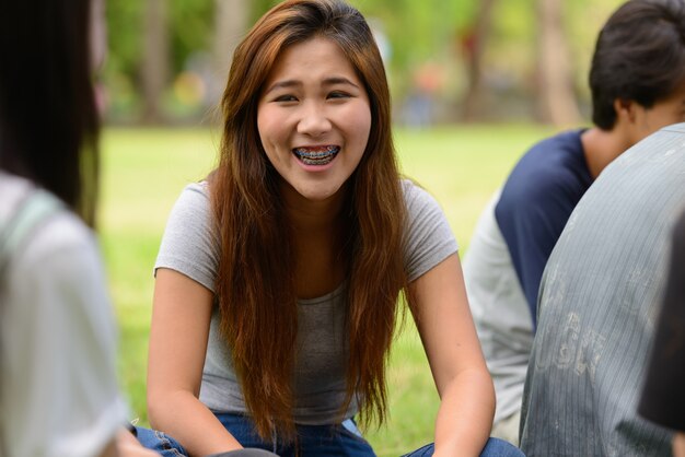 Gruppo di giovani amici asiatici uscire e rilassarsi insieme al parco all'aperto