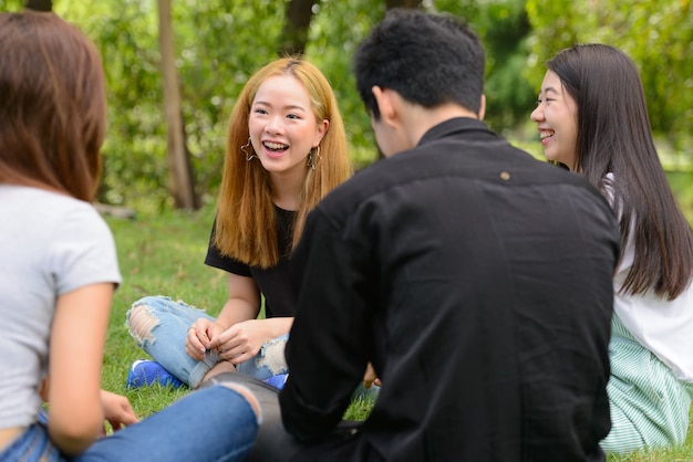 Gruppo di giovani amici asiatici uscire e rilassarsi insieme al parco all'aperto