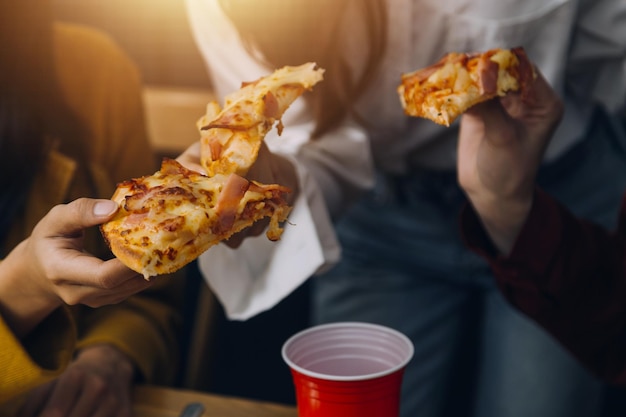 Gruppo di giovani amici che mangiano pizza a casa e si divertono