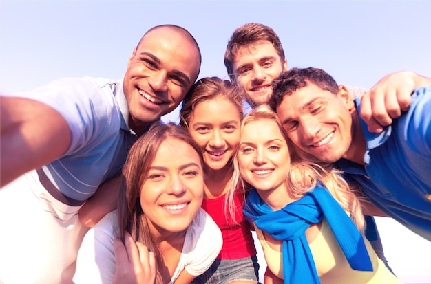 Gruppo di giovani amici che prendono selfie all'aperto