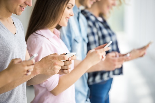 Gruppo di giovani amici positivi che utilizzano i loro telefoni.