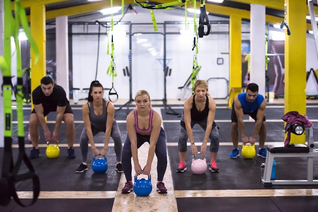 gruppo di giovani atleti sani facendo esercizi con kettlebell presso cross fitness studio