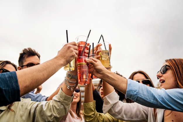 Gruppo di giovani che brindano con cocktail in bicchieri di plastica