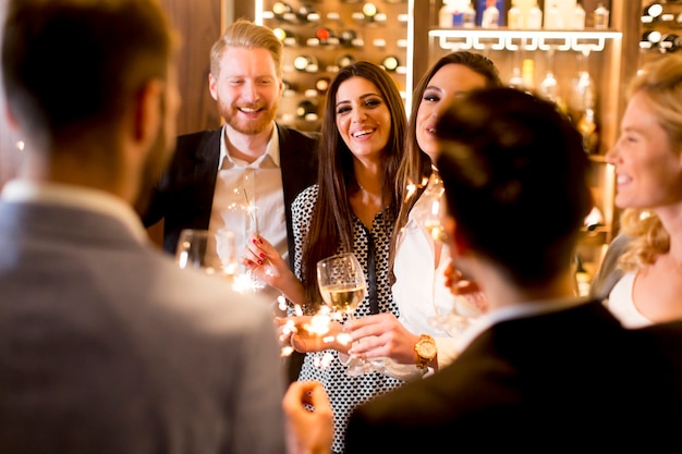 Gruppo di giovani che celebra e brindando con vino bianco