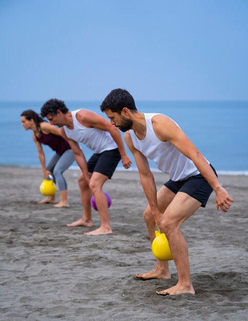 gruppo di giovani che si esercitano in spiaggia con le campane del bollitore