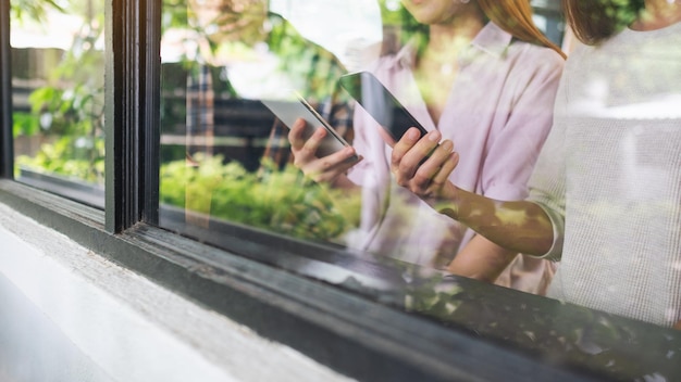 Gruppo di giovani che tengono e usano i loro telefoni cellulari seduti insieme all'interno