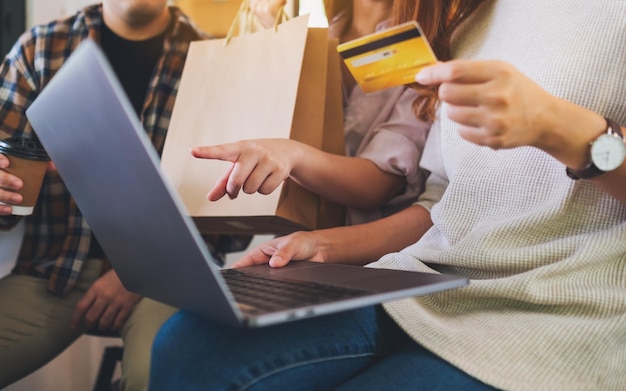 Gruppo di giovani che utilizzano laptop e carta di credito per lo shopping online insieme
