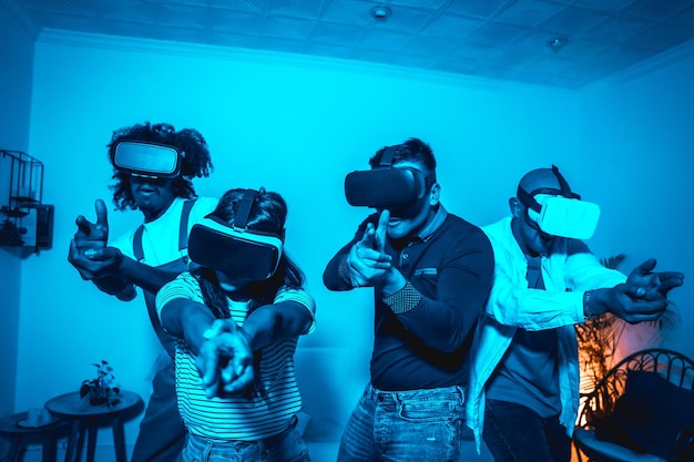 Gruppo di giovani con occhiali vr in un gioco di realtà virtuale in una luce blu che mira con le mani come pistole futuristiche o concetto di tecnologia scientifica