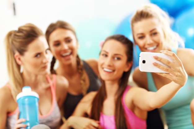 gruppo di giovani donne che si fanno selfie in palestra dopo l'allenamento