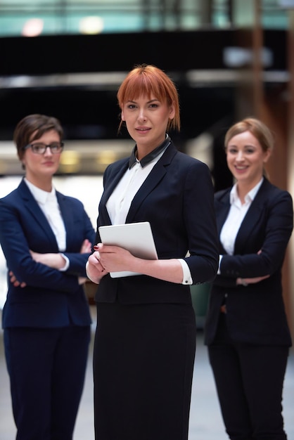 gruppo di giovani donne d'affari, squadra in piedi in un moderno ufficio luminoso e che lavora su tablet