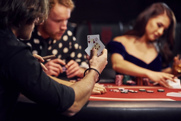 Gruppo di giovani eleganti che giocano a poker nel casinò insieme