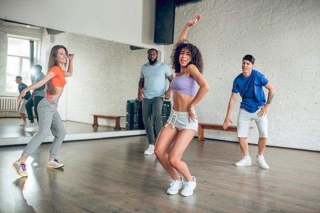 Gruppo di giovani energici in abbigliamento sportivo e scarpe da ginnastica impegnati nella danza