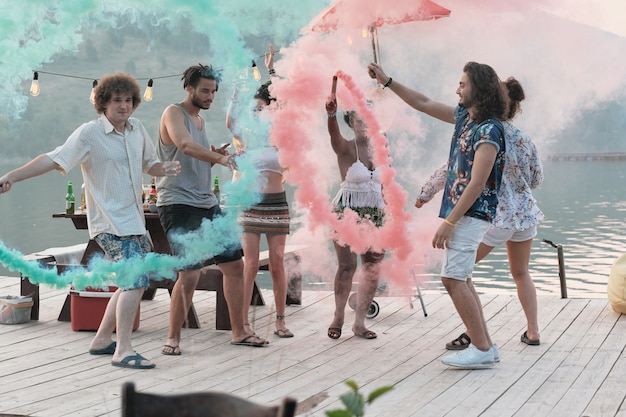 Gruppo di giovani felici in piedi su un molo e divertirsi durante una festa all'aperto