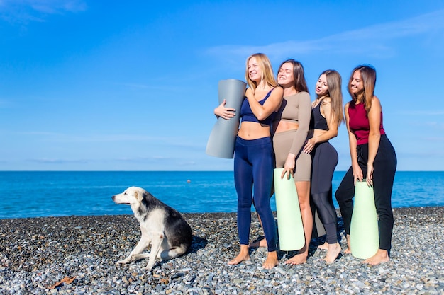 Gruppo di giovani femmine che praticano yoga in riva al mare