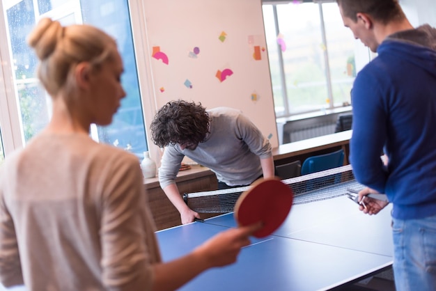 gruppo di giovani imprenditori che giocano a ping pong presso l&#39;ufficio creativo moderno