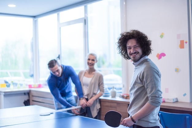 gruppo di giovani imprenditori che giocano a ping pong presso l&#39;ufficio creativo moderno