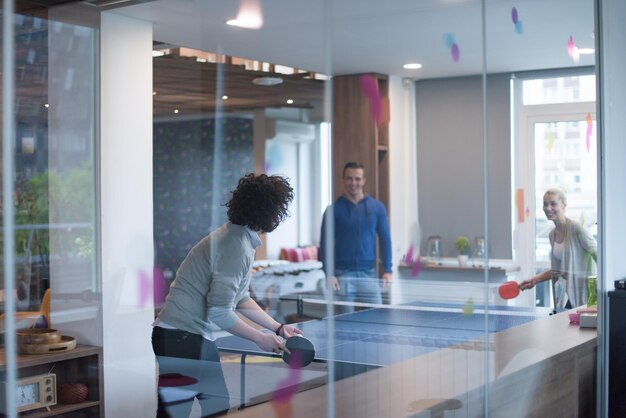 gruppo di giovani imprenditori che giocano a ping pong presso l&#39;ufficio creativo moderno