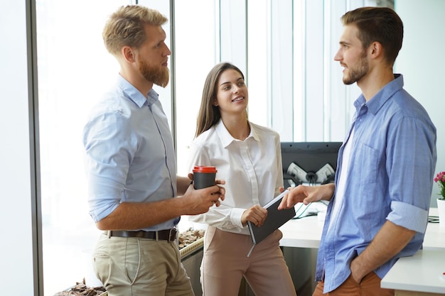 Gruppo di giovani moderni in abbigliamento casual intelligente che hanno una riunione di brainstorming mentre si trovano nell'ufficio creativo