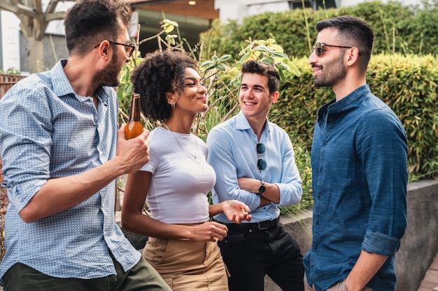 Gruppo di giovani multiculturali che bevono birre e parlano all'aperto