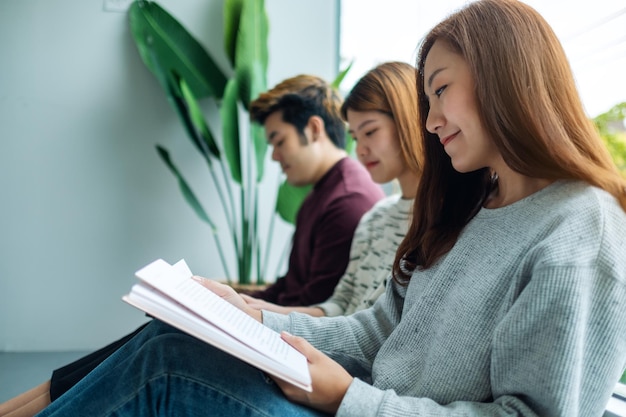 Gruppo di giovani seduti e divertito a leggere libri insieme