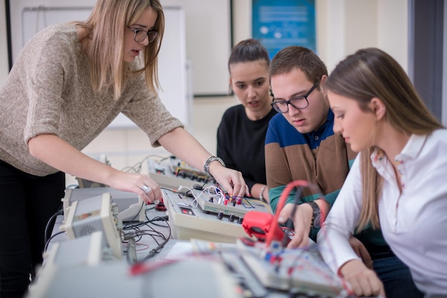 Gruppo di giovani studenti che fanno pratica tecnica professionale con l'insegnante nell'aula elettronica, concetto di istruzione e tecnologia