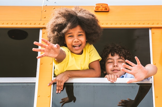 Gruppo di giovani studenti che frequentano la scuola primaria su uno scuolabus giallo - Bambini delle scuole elementari che si divertono