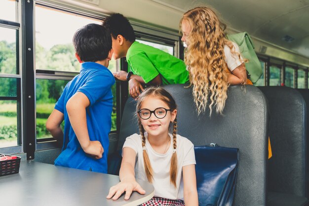 Gruppo di giovani studenti che frequentano la scuola primaria su uno scuolabus giallo - Bambini delle scuole elementari che si divertono